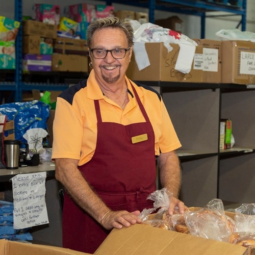 Image of man standing next to a box of food.
